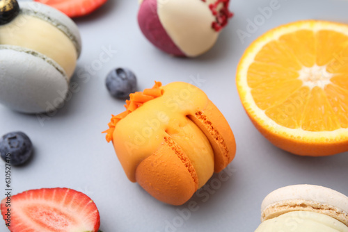 Delicious macarons, fruits and berries on light blue table, closeup