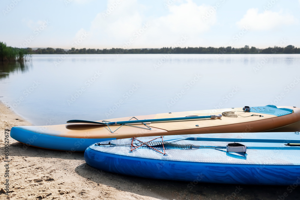 SUP boards with paddles on river shore