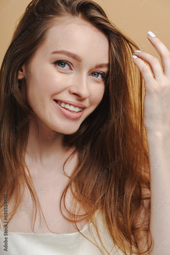 Portrait of beautiful woman with long hair smiling looking at camera isolated on beige background Portrait of beautiful woman with long hair smiling looking at camera isolated on beige background