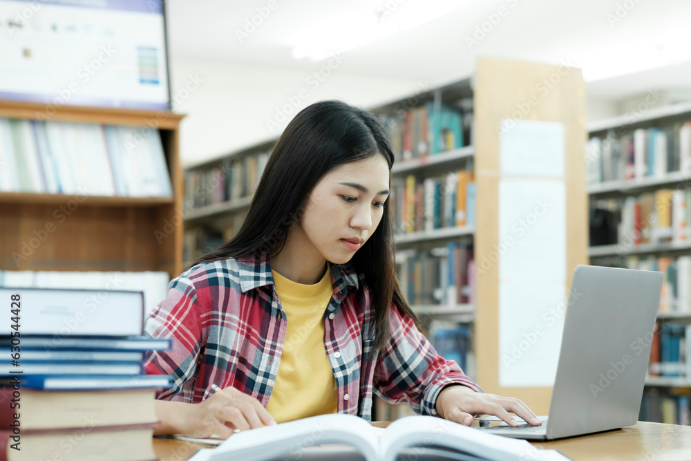 Young university student using laptop for online learning, searching and learning at library. Young university student using laptop for online learning, searching and learning at library.