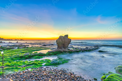 Rocky beach and green moss in sunrise sky at a beautiful beach in central Vietnam. Seascape of Vietnam Strange rocks. photo