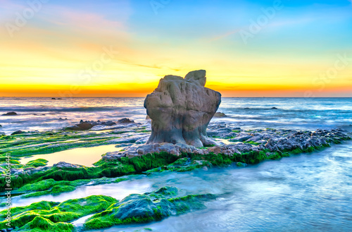 Rocky beach and green moss in sunrise sky at a beautiful beach in central Vietnam. Seascape of Vietnam Strange rocks. photo