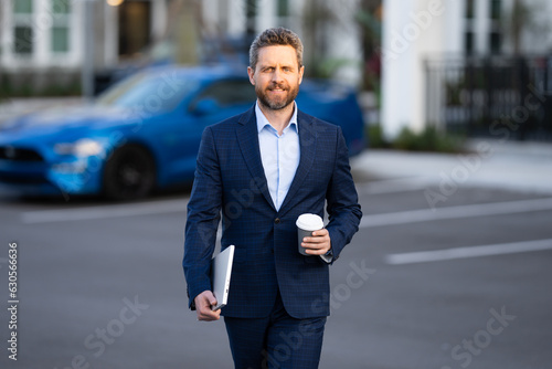 Outdoor portrait business man in classic suit. Fashionable man walking outdoors. Businessman in fashion suit walking in city. Business fashion street style. Man in trendy suit. Business man in suit.