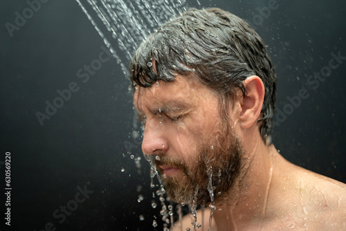 Middle aged man washing hair in bath. Guy bathing shower head in bathtub. Face in foam in shower. Bathing man taking shower. Closeup guy showering. Shower concept. Man is under water drops in showers.