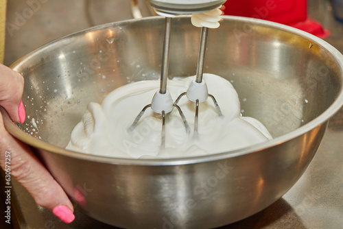 Chef whips the egg whites with mixer in bowl