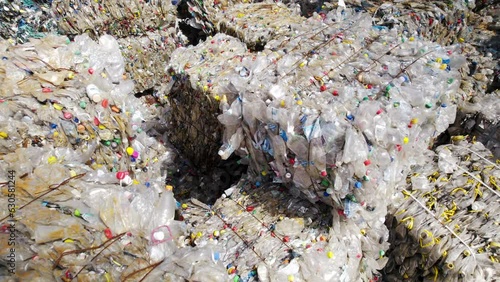 Multiple cubes of compressed transparent plastic garbage at waste recycling factory in open air