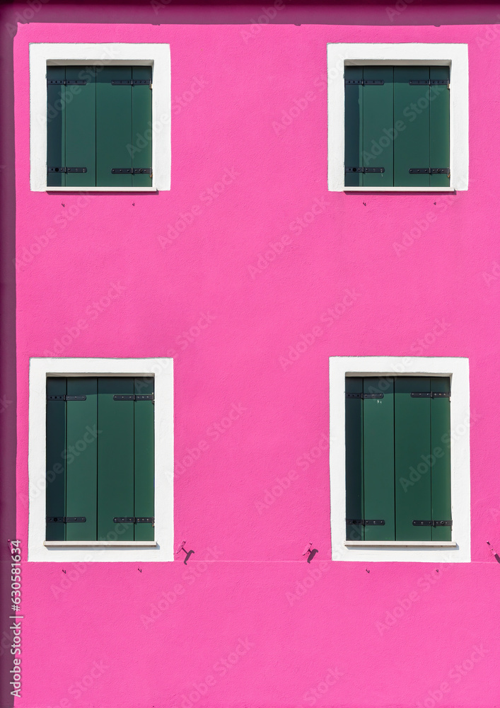 Detail with a pink colorful house window with green painted wooden shutters in Burano, Italy.