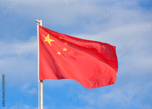 Bandera de China ondeando en el viento contra el cielo azul y nubes  