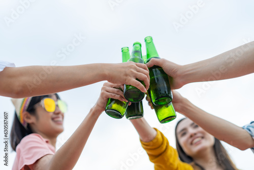 Asian Friends drinking beer on sea beach.Group of young people having fun drinking party on beach in twilight sunset,Summer Holiday 