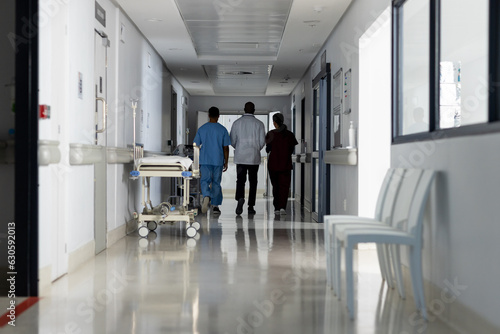 Diverse doctors discussing work and walking through corridor at hospital