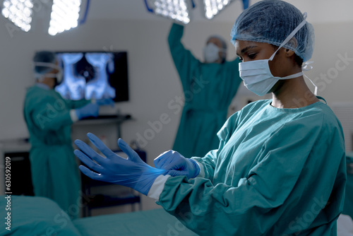 African american female surgeon wearing surgical gown and gloves in operating theatre at hospital