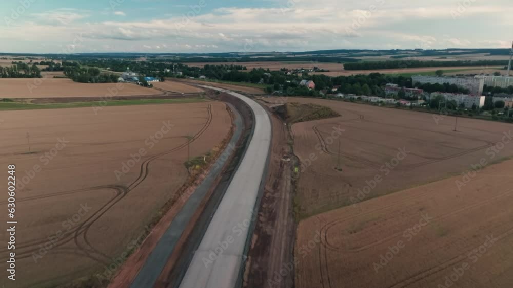 Newly built road. Bypass through the town of Svitavy leading to Brno. Aerial view of finishing works at sunset in summer. In the background, the town of Svitavy and grain fields. Newly built road. Bypass through the town of Svitavy leading to Brno. Aerial view of finishing works at sunset in summer. In the background, the town of Svitavy and grain fields.