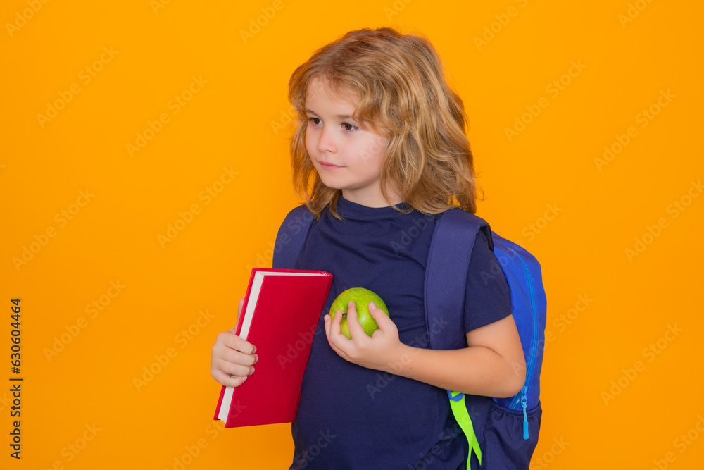 Knowledge day. School boy, isolated on yellow studio background. Back to school. Funny little boy from elementary school with book. Education. Knowledge day. School boy, isolated on yellow studio background. Back to school. Funny little boy from elementary school with book. Education.