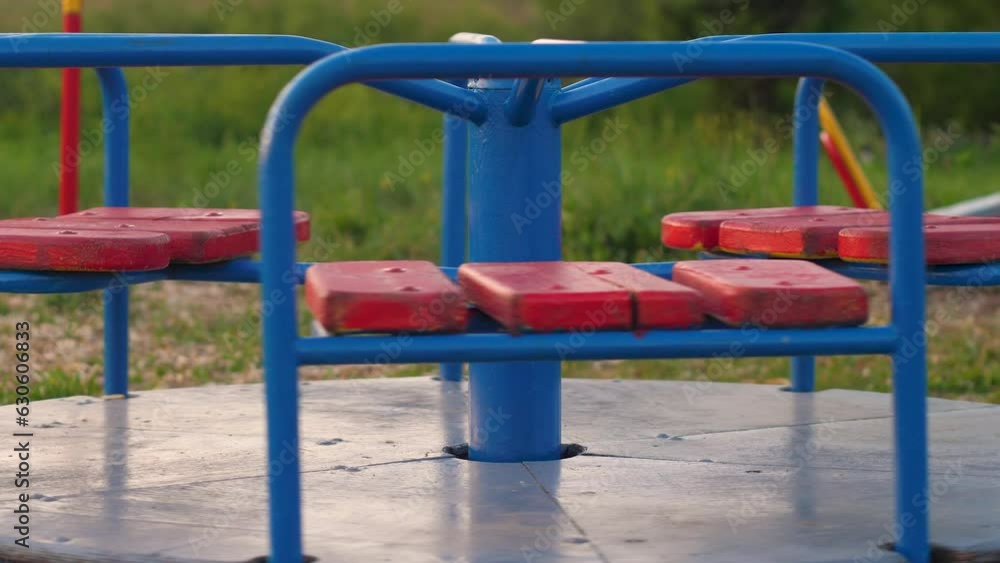 deserted children's iron carousel rotates. an empty playground without children, the end of games and entertainment. deserted children's iron carousel rotates. an empty playground without children, the end of games and entertainment.