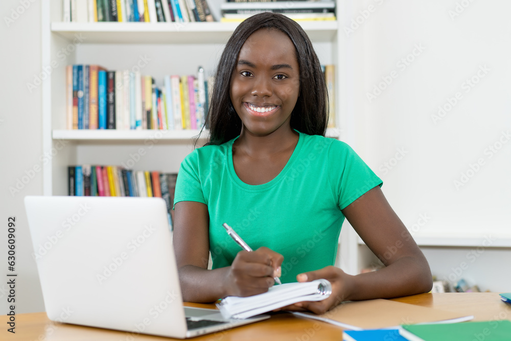 Laughing black female student learning with books and computer Laughing black female student learning with books and computer