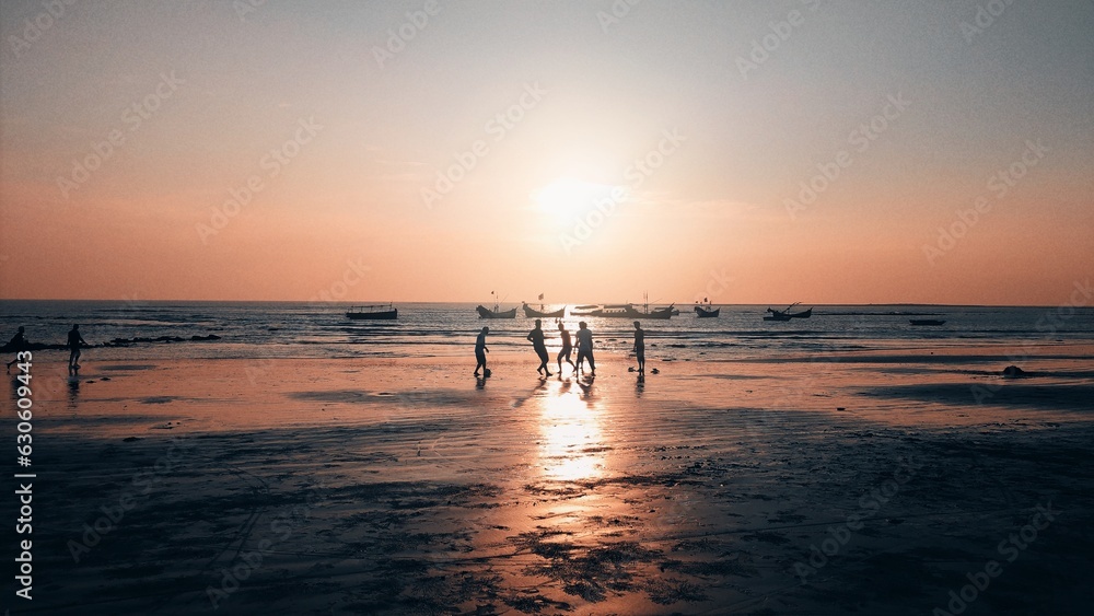 A Candid of a Truly Playful Moment of Boys Playing Football on the Beach During the Sunset on their Vacation. A Golden Memory During the Golden Hour.