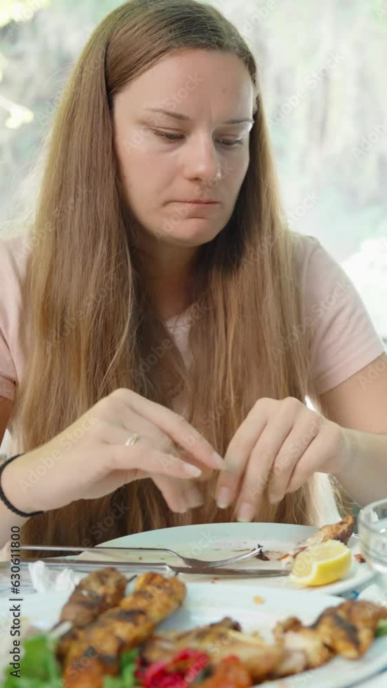 The young woman bites off a flatbread and eats a salad. Cafe on the water with a view of the waterfall. Vertical, Social Media The young woman bites off a flatbread and eats a salad. Cafe on the water with a view of the waterfall. Vertical, Social Media