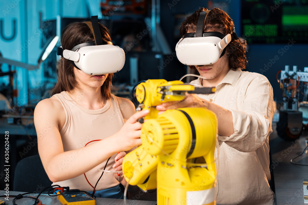 Young man and woman in VR glasses doing experiments in robotics in a laboratory