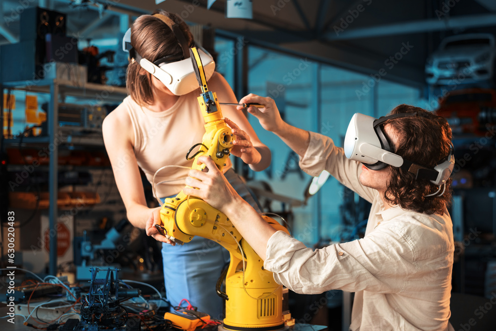 Young man and woman in VR glasses doing experiments in robotics in a laboratory