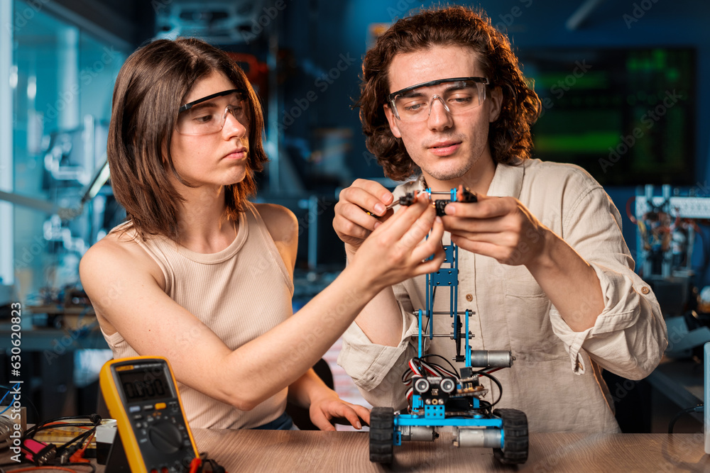 Young man and woman doing experiments in robotics in a laboratory