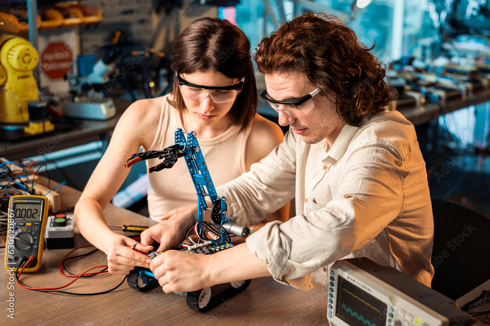 Young man and woman doing experiments in robotics in a laboratory