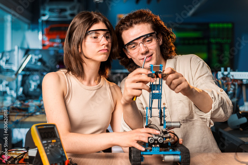 Young man and woman doing experiments in robotics in a laboratory
