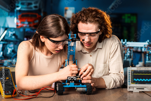 Obraz na płótnie Young man and woman doing experiments in robotics in a laboratory w salonie