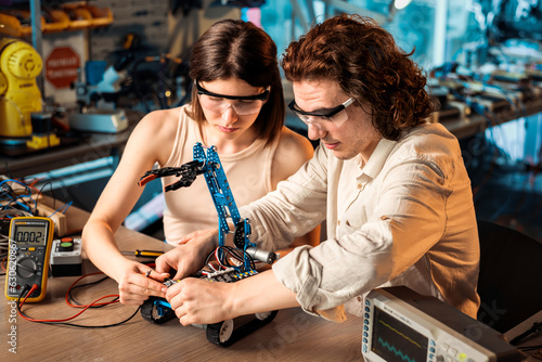 Obraz na płótnie Young man and woman doing experiments in robotics in a laboratory w salonie
