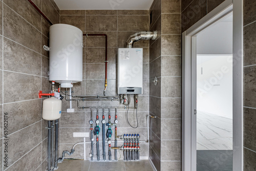 Copper valves, stainless ball valves, detectors of water pressure and plastic pipes of central heating system and water pipes with thermal insulation in the boiler room in apartment during under.