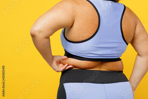 Close up rear view young chubby overweight plus size big fat fit woman wears blue top warm up train show skin folds on back isolated on plain yellow background studio home gym. Workout sport concept.