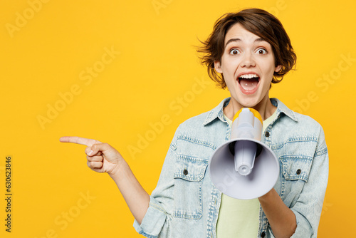 Принти на полотні Young happy woman she wear green t-shirt denim shirt casual clothes hold in hand megaphone scream announces discounts sale Hurry up point aside isolated on plain yellow background