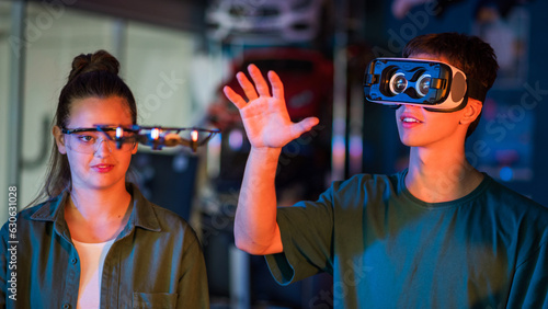 Obraz na płótnie Teens doing experiments in robotics in a laboratory. Boy in VR headset holding a small drone. Red and blue illumination w salonie