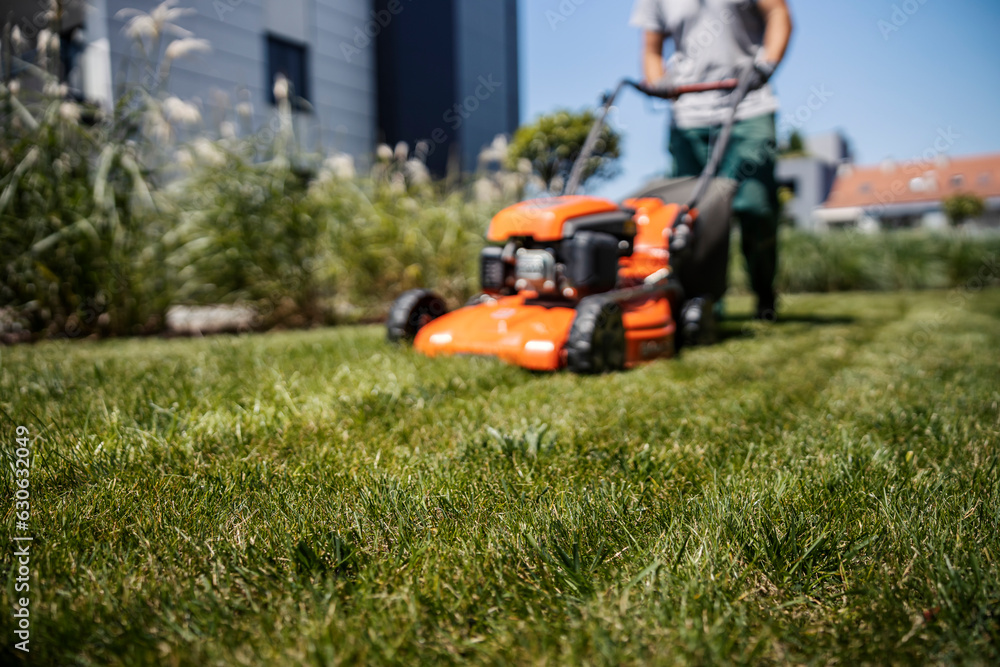 Blurry picture of a man using a lawn mower for maintaining the grass. Blurry picture of a man using a lawn mower for maintaining the grass.