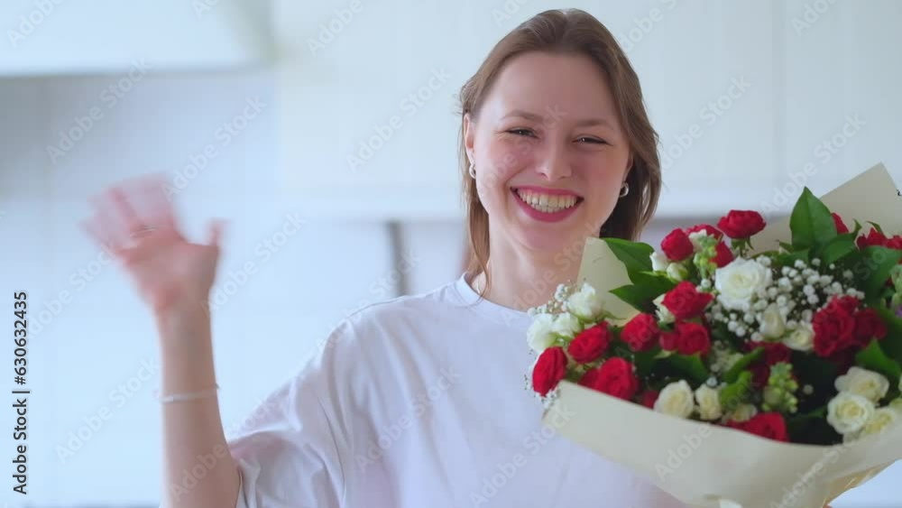 Beautiful woman holds a bouquet of flowers and looks at camera stand on kitchen. Beautiful woman holds a bouquet of flowers and looks at camera stand on kitchen.