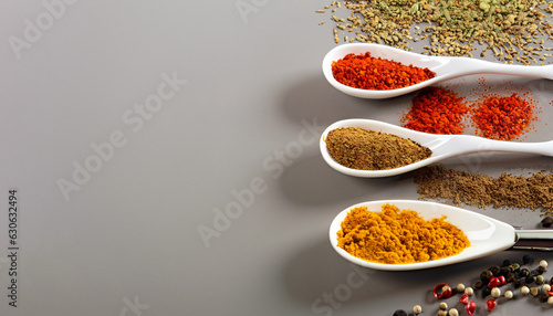 Cooking background with spoon with different types of spices. Asian spices like curry, pepper and paprika on white spoon. Top view with copy space. Concept of gourmet, organic and asian cuisine.