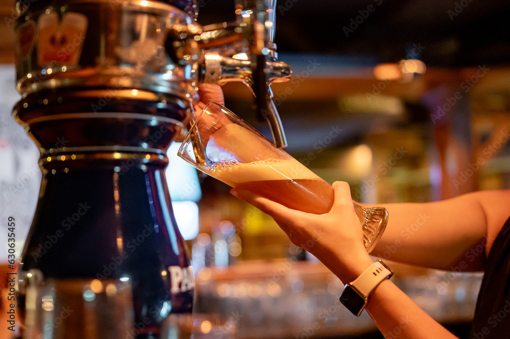 bartender woman hand at beer tap pouring a draught beer in glass serving in a restaurant or pub
