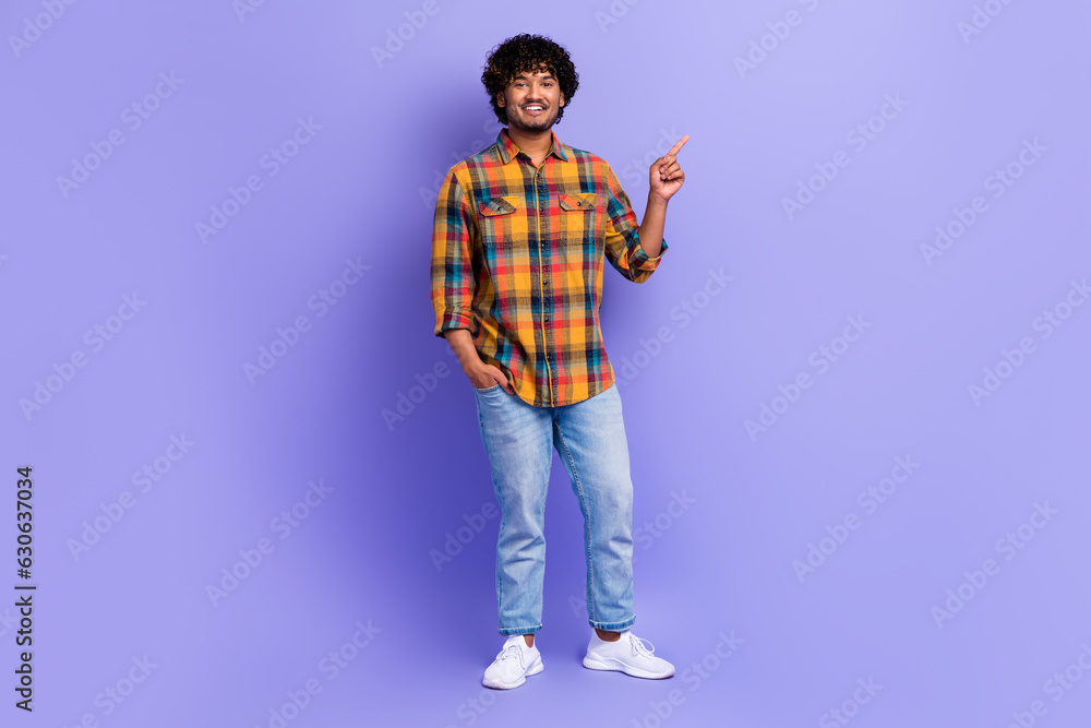 Full length photo of good mood man dressed plaid shirt denim pants indicating at product empty space isolated on purple color background Full length photo of good mood man dressed plaid shirt denim pants indicating at product empty space isolated on purple color background
