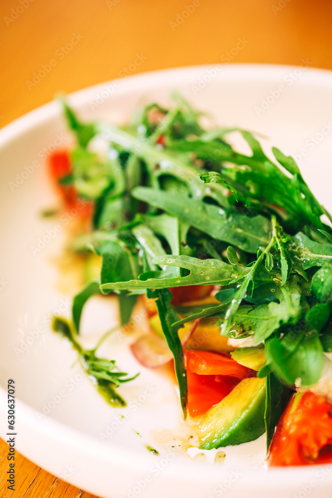 fresh salad with arugula and avocado on the table. refreshing salad with fresh herbs and vegetables fresh salad with arugula and avocado on the table. refreshing salad with fresh herbs and vegetables