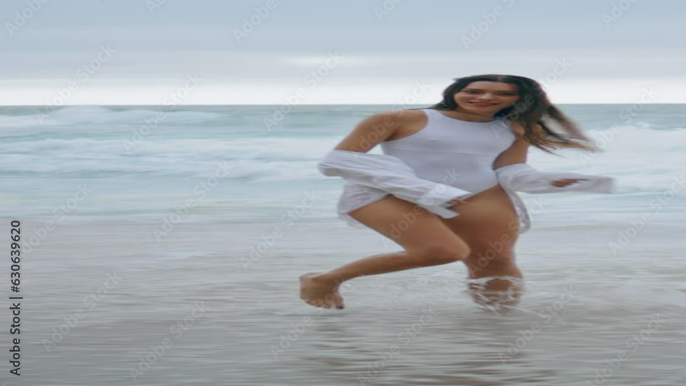 Playful girl running sea waves enjoying weekend. Woman jumping on beach vertical Playful girl running sea waves enjoying weekend. Woman jumping on beach vertical
