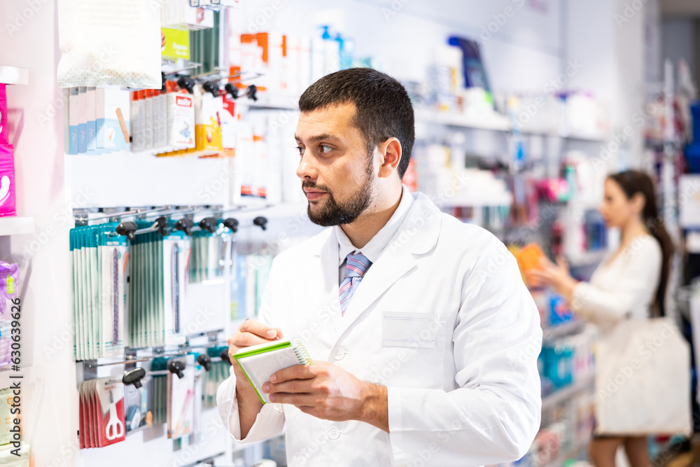 Male pharmacist checking assortment of drugs in pharmacy