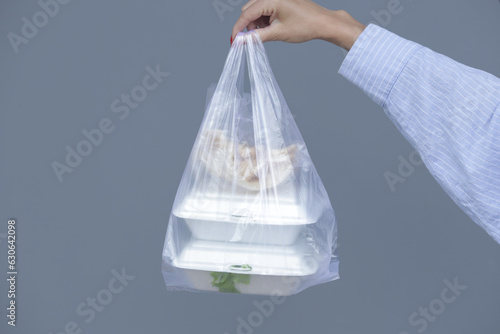 Woman's hands holding PVC plastic bag with takeaway foam lunch boxes. Single use food containers, donation concept.