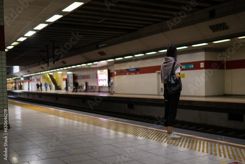 Young woman waits at metro station while the train arrives photo