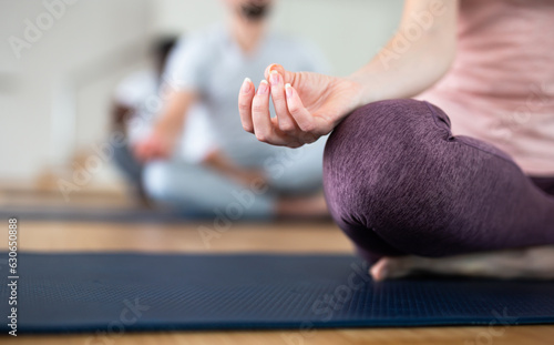 Closeup of female hand with fingers folded in mudra. Hand lying on knee while woman sitting in yoga position Padmasana..