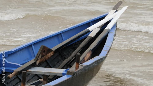 Bow of currach boat and traditional wooden oars piled onto front as waves crash photo