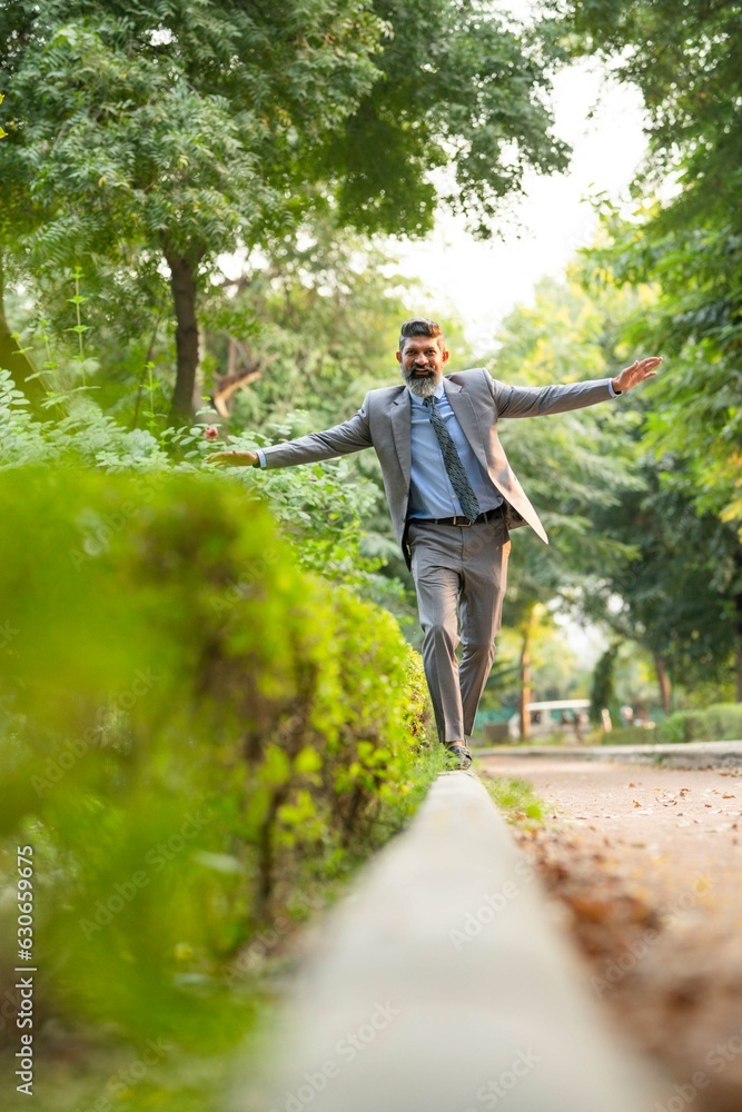 Indian businessman walking at park and giving happy expression Indian businessman walking at park and giving happy expression