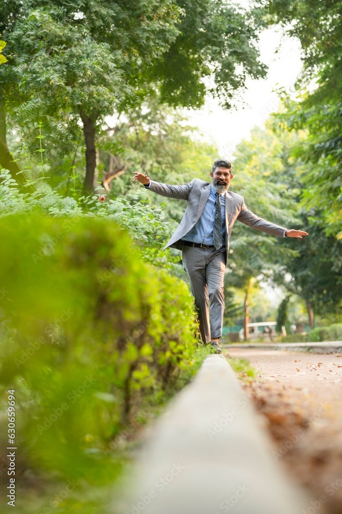 Indian businessman walking at park and giving happy expression Indian businessman walking at park and giving happy expression