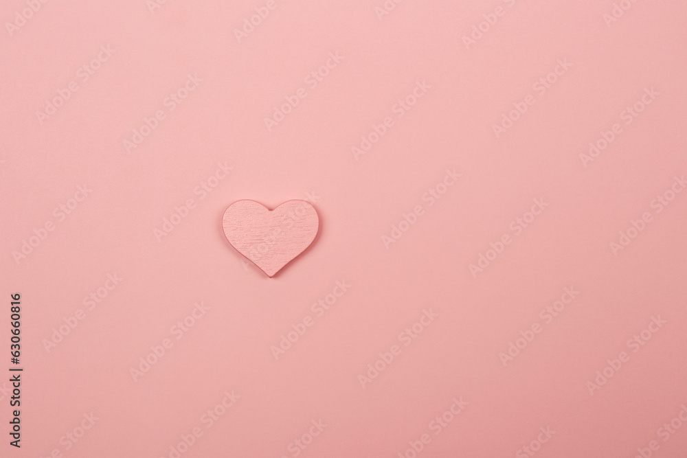 Pink color wooden heart isolated on the bright solid pink fond background