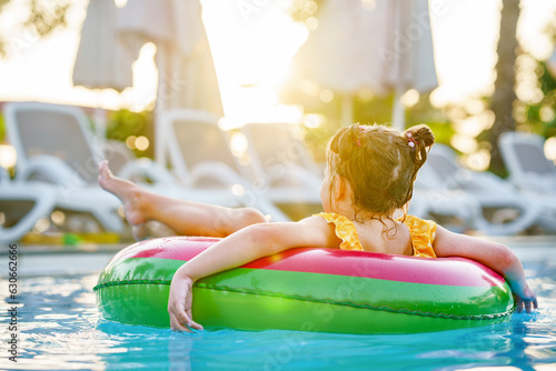 Happy little girl with inflatable toy ring float in swimming pool. Little preschool child learning to swim and dive in outdoor pool of hotel resort. Healthy sport activity and fun for children. © Irina Schmidt