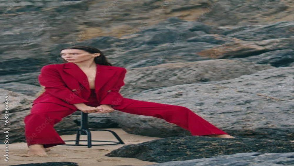 Woman posing beach cliffs in red suit cloudy day. Model sitting chair vertical Woman posing beach cliffs in red suit cloudy day. Model sitting chair vertical