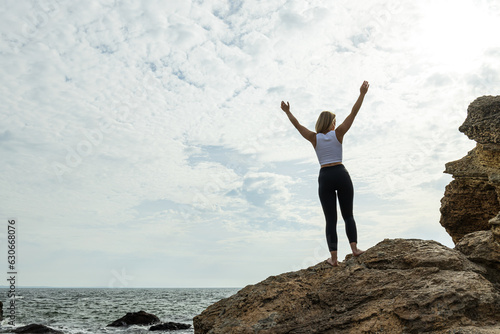 The girl on the rock holds her hands to the mountain  to the sun